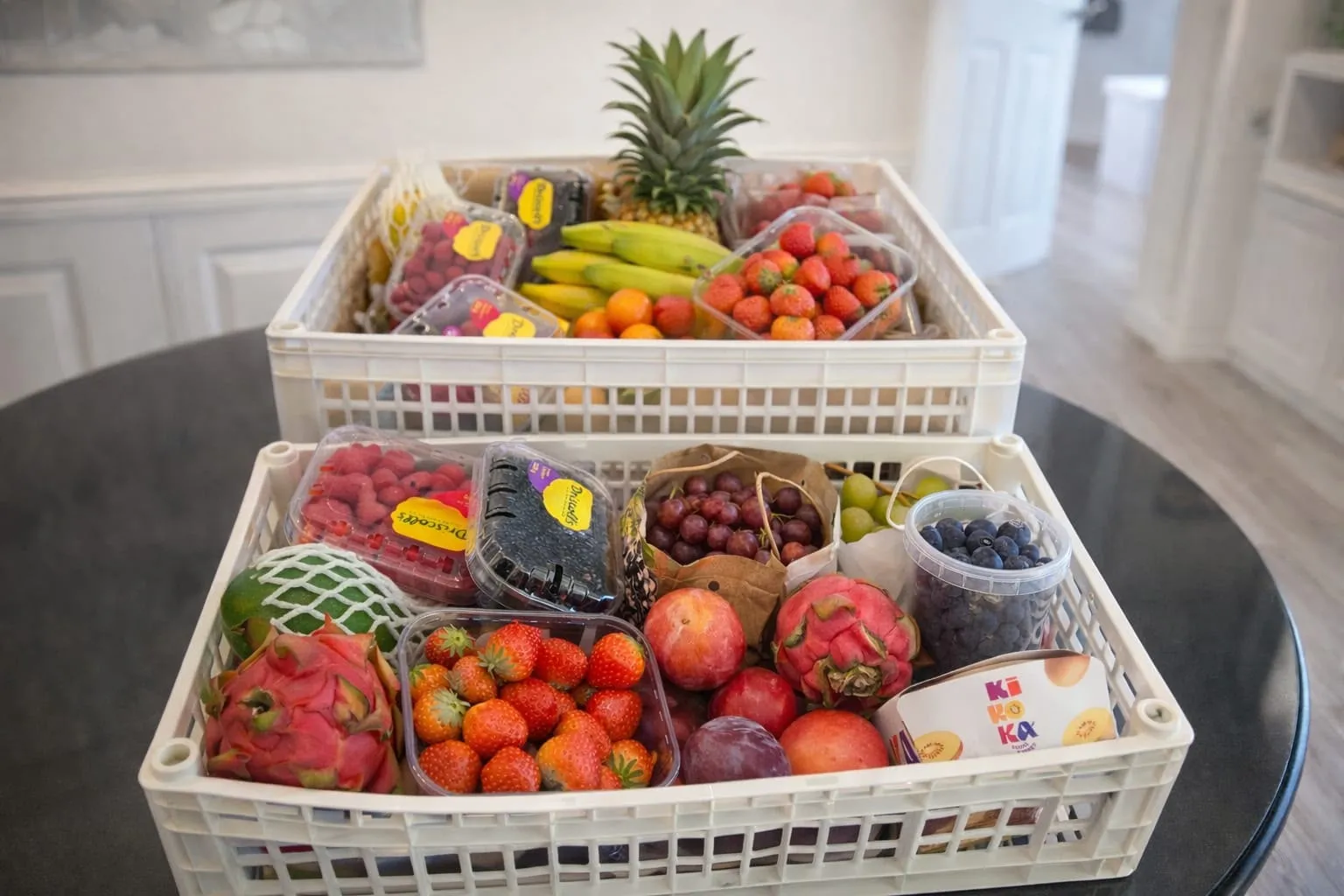 Twee witte kratten met dragon fruit, aardbeien, frambozen, druiven en ananas